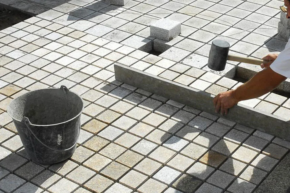 Worker setting paving slabs on a prepared surface