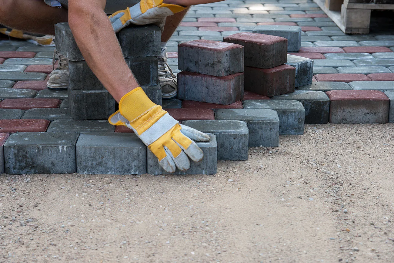 A member of the S J P Paving team laying block paving by hand
